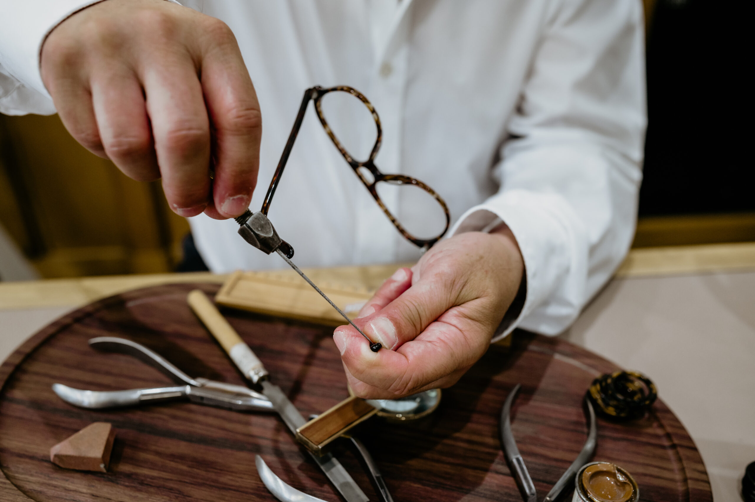 Artisan opticien réparant monture de lunettes avec outils traditionnels